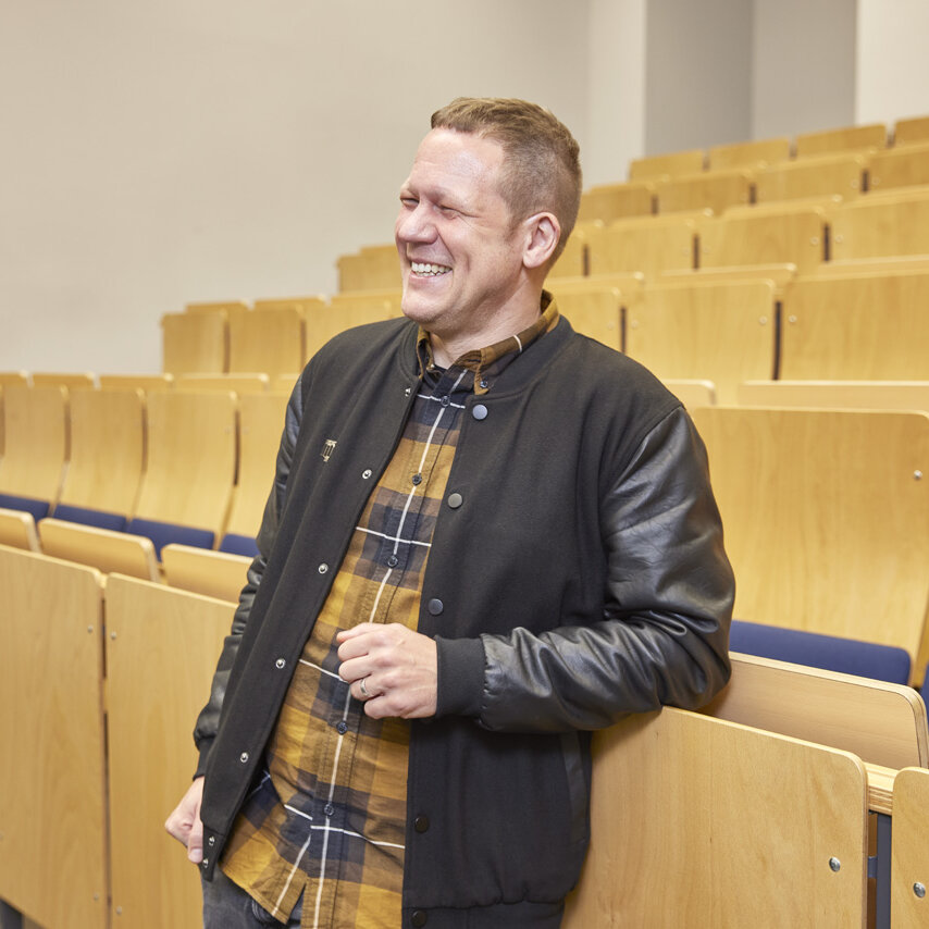 Prof. Dr. Ulrich Pfeiffer steht in einem leeren Hörsaal.