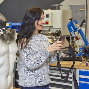 Studentin arbeitet in einem Labor mit einem technischen Gerät neben einer silbernen Oberkörperpuppe.