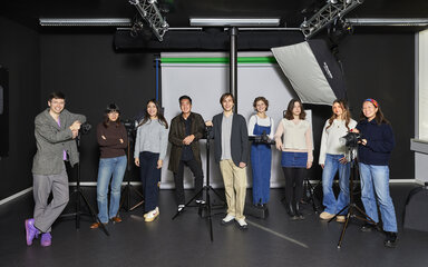 International Gruppe von Studierenden posiert zwischen Beleuchtungsausrüstung im Fotostudio.