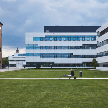 Campus Kleve mit einer großen Rasenfläche und im Hintergrund befinden sich die modernen Hochschulgebäude und Bibliothek.