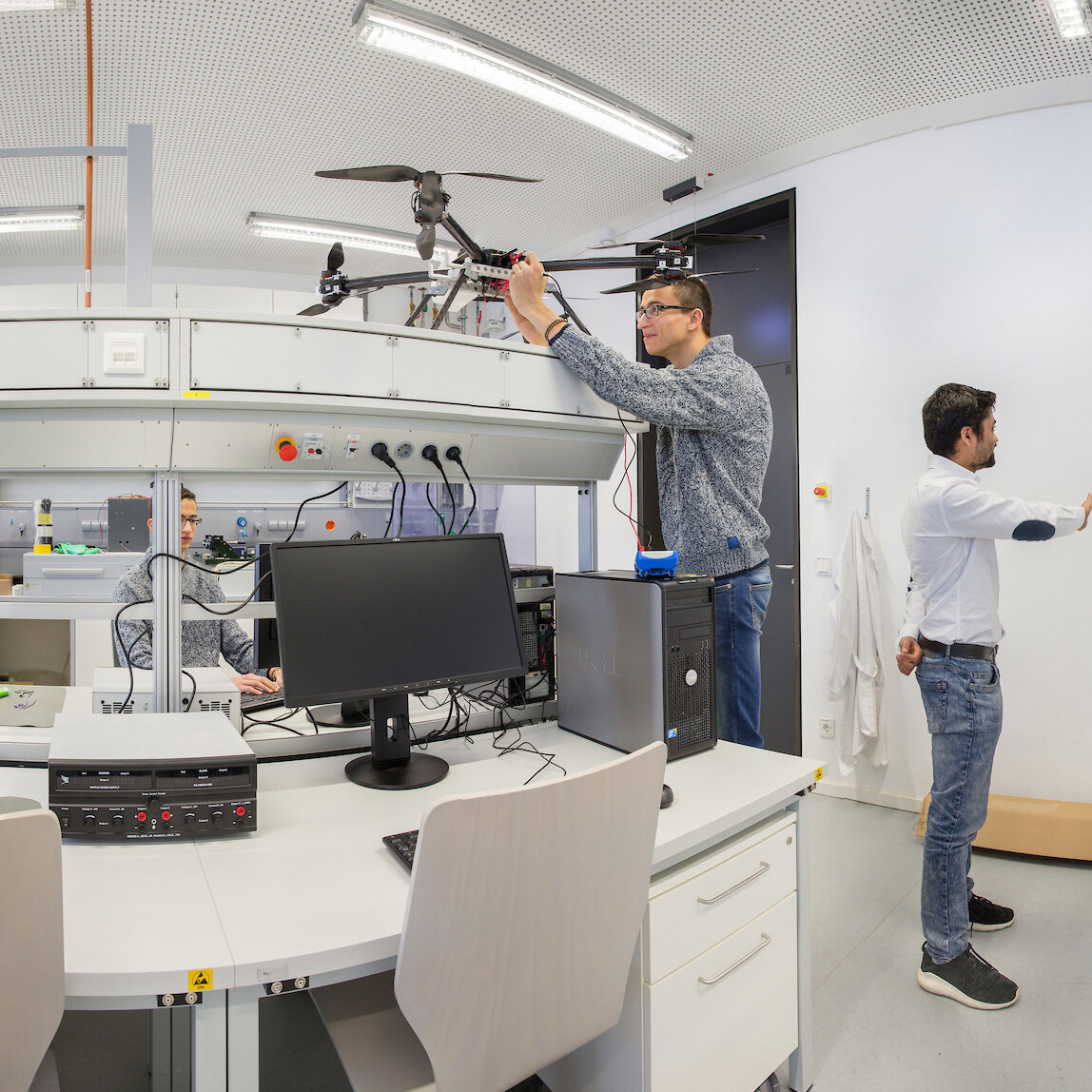 Mehrere Personen arbeiten an verschiedenen Arbeitsplätzen mit Computern und technischer Ausstattung im Internet of Things Labor.