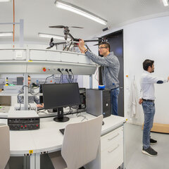 Several people are working at various workstations using computers and technical equipment in the Internet of Things laboratory.