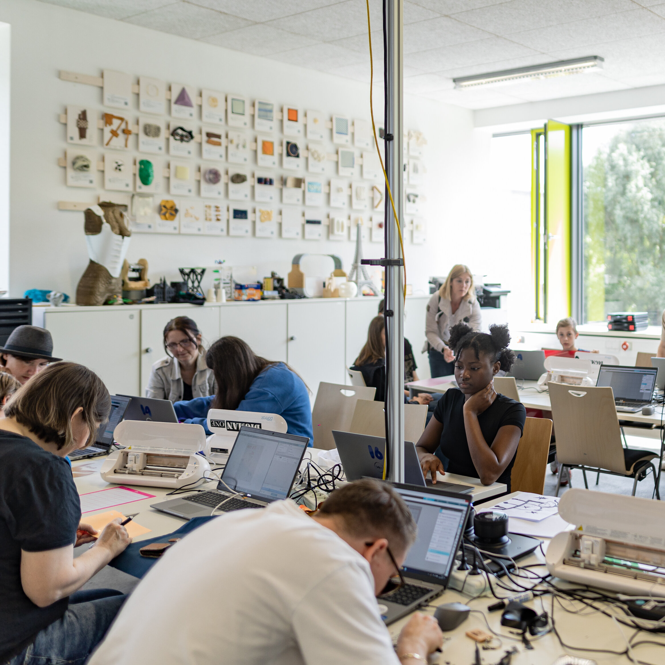 Eine Gruppe von Menschen arbeitet kreativ an Tischen im FabLab