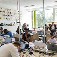 A group of people are working creatively at tables in the FabLab