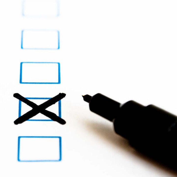A black pen lies on a sheet of paper with boxes to tick