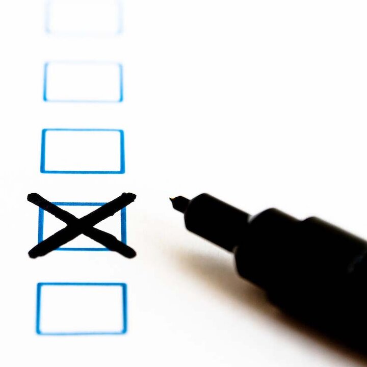 A black pen lies on a sheet of paper with boxes to tick