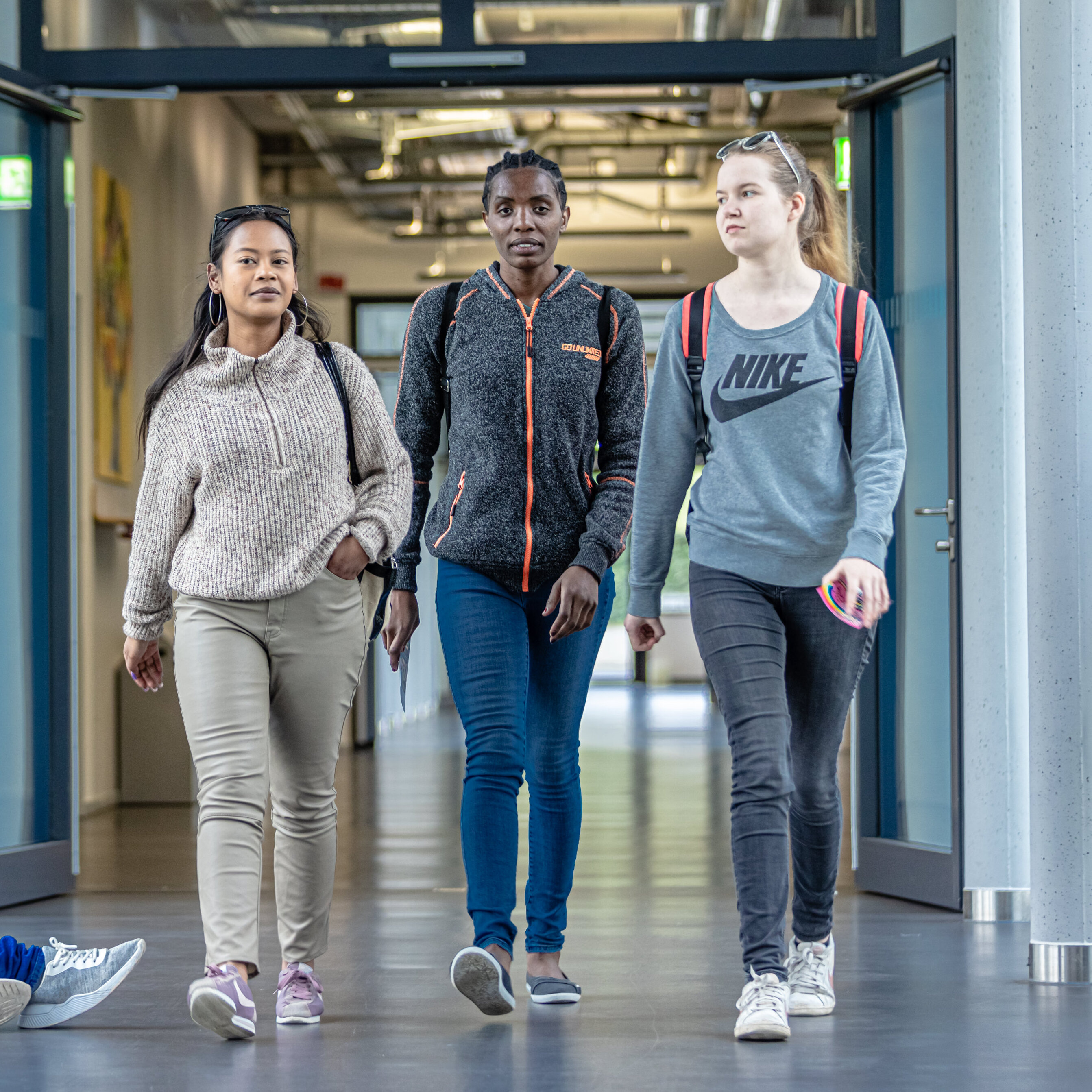 Drei Studierende laufen im Flus des Fakultätsgebäudes entlang