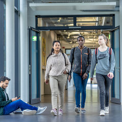 Three students are walking down the hallway of the faculty building