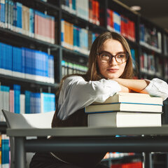Studentin sitzt in der Bibliothek Kamp-Lintfort und guckt verträumt in die Ferne