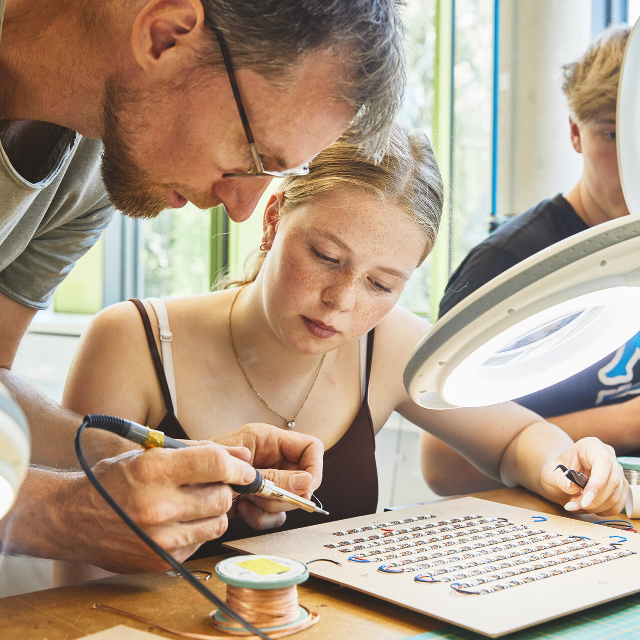 Mehrere Studierende die konzentriert in einem Labor arbeiten und miteinander sprechen.