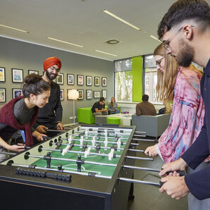 Gruppe von Studierenden spielt Tischfußball im Synapse-Raum.