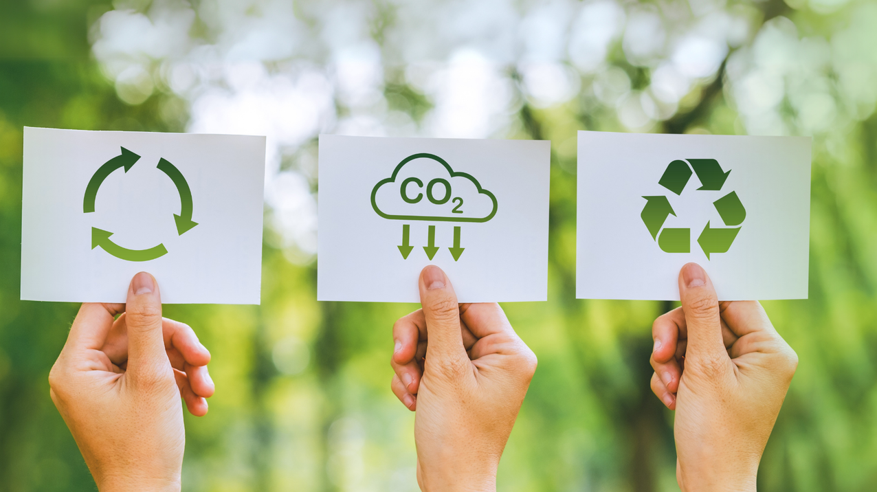 Drei Hände halten je einen Zettel mit Recyclingsymbolen vor einem grünen Naturhintergrund, links oben im Bild ist das Studiengangsicon für Engineering for Sustainability zu sehen.