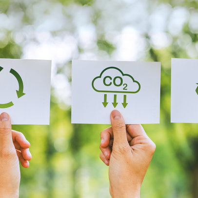 Drei Hände halten je einen Zettel mit Recyclingsymbolen vor einem grünen Naturhintergrund, links oben im Bild ist das Studiengangsicon für Engineering for Sustainability zu sehen.