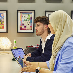 Zwei Studierende arbeiten nebeneinander an Laptops