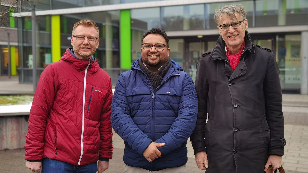 Gruppenfoto der Projektpartner vor einem Hochschulgebäude. Von links nach rechts: Prof. Dr. Torsten Niechoj, Arslan Austin und Prof. René Kemp.