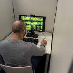 A man is sitting in a booth in front of a computer screen 