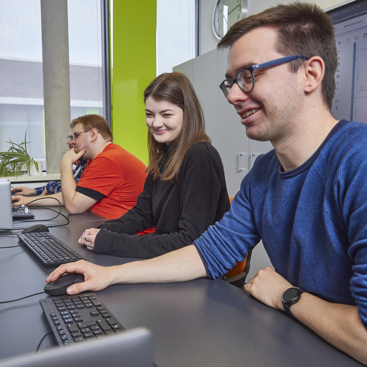 Zwei Studierende arbeiten gemeinsam an Computern in einem modernen Computerraum.