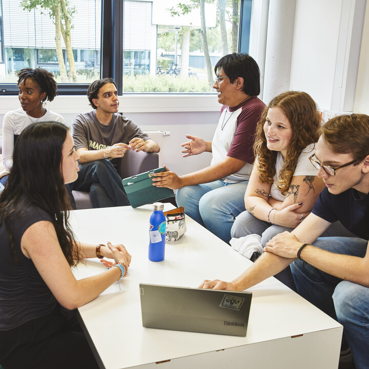 Eine Gruppe Studierender sitzen in einem Aufenthaltsraum und unterhalten sich