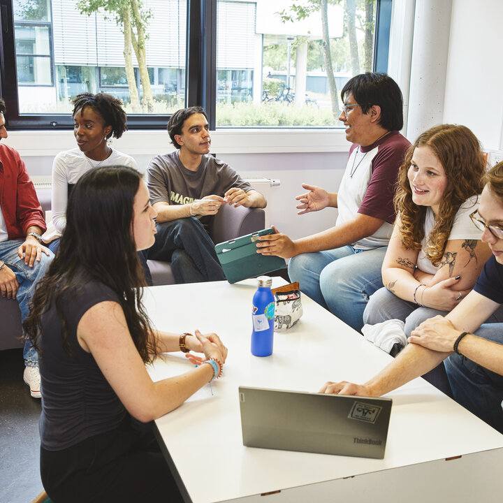 A group of students are sitting in a common room, chatting