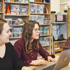 Two students are working on a laptop