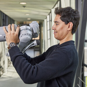 Nahaufnahme eines Studenten, der einen vierbeinigen Roboter hält.