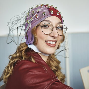 Eine Studentin hat eine Haube auf dem Kopf, von der ganz viele Kabel abgehen.