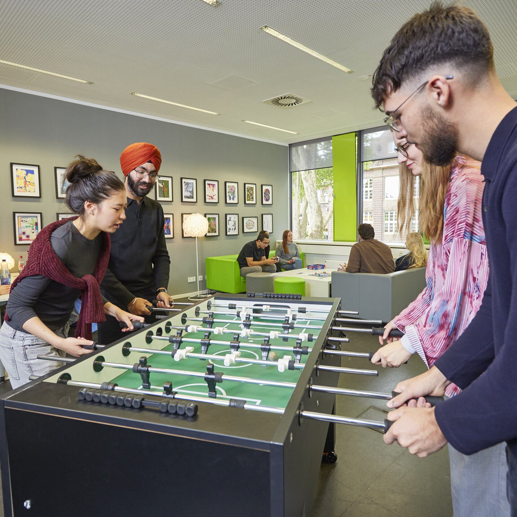 Gruppe von Studierenden spielt Tischfußball im Synapse-Raum.