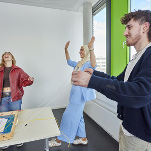 Drei Studierende haben gemeinsam Spaß bei einer spielerischen Aktivität im Labor.