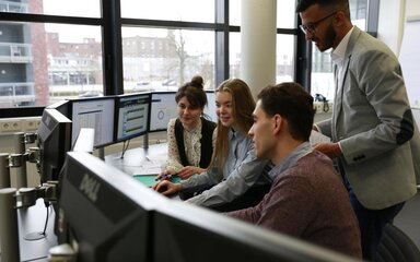 Mehrere Studierende sitzen vor einer Reihe von Computermonitoren