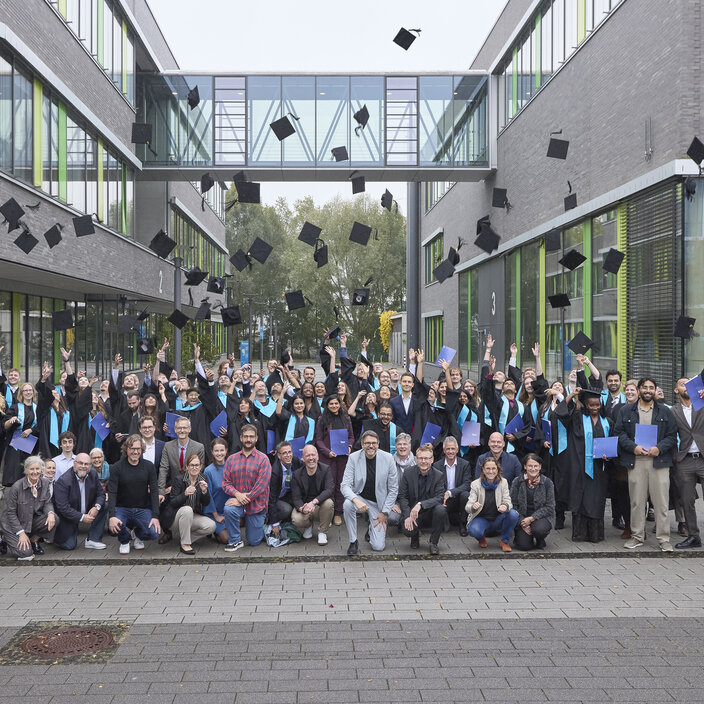 Studierende werfen auf den Campus ihre Hüte in die Luft