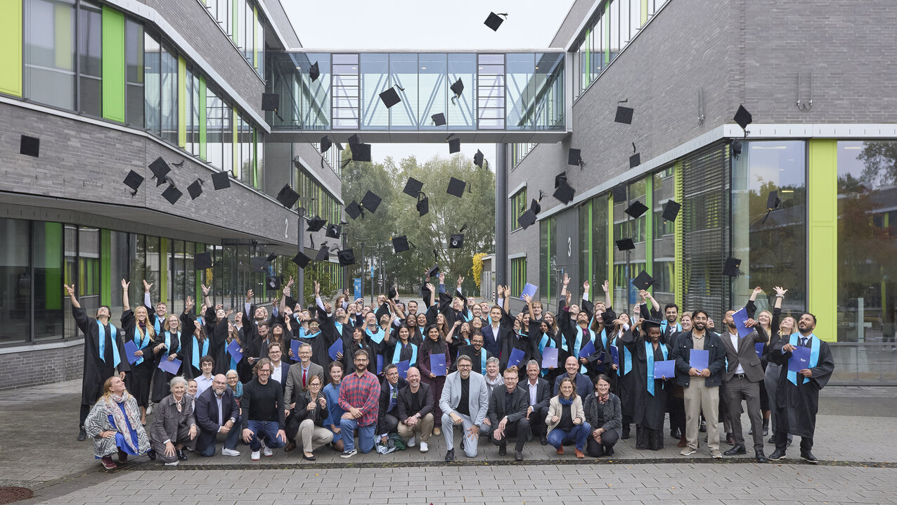 Studierende werfen auf den Campus ihre Hüte in die Luft
