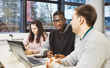 Vielfältige Karrieren Studierende sitzen zusammen vor einem Laptop und arbeiten