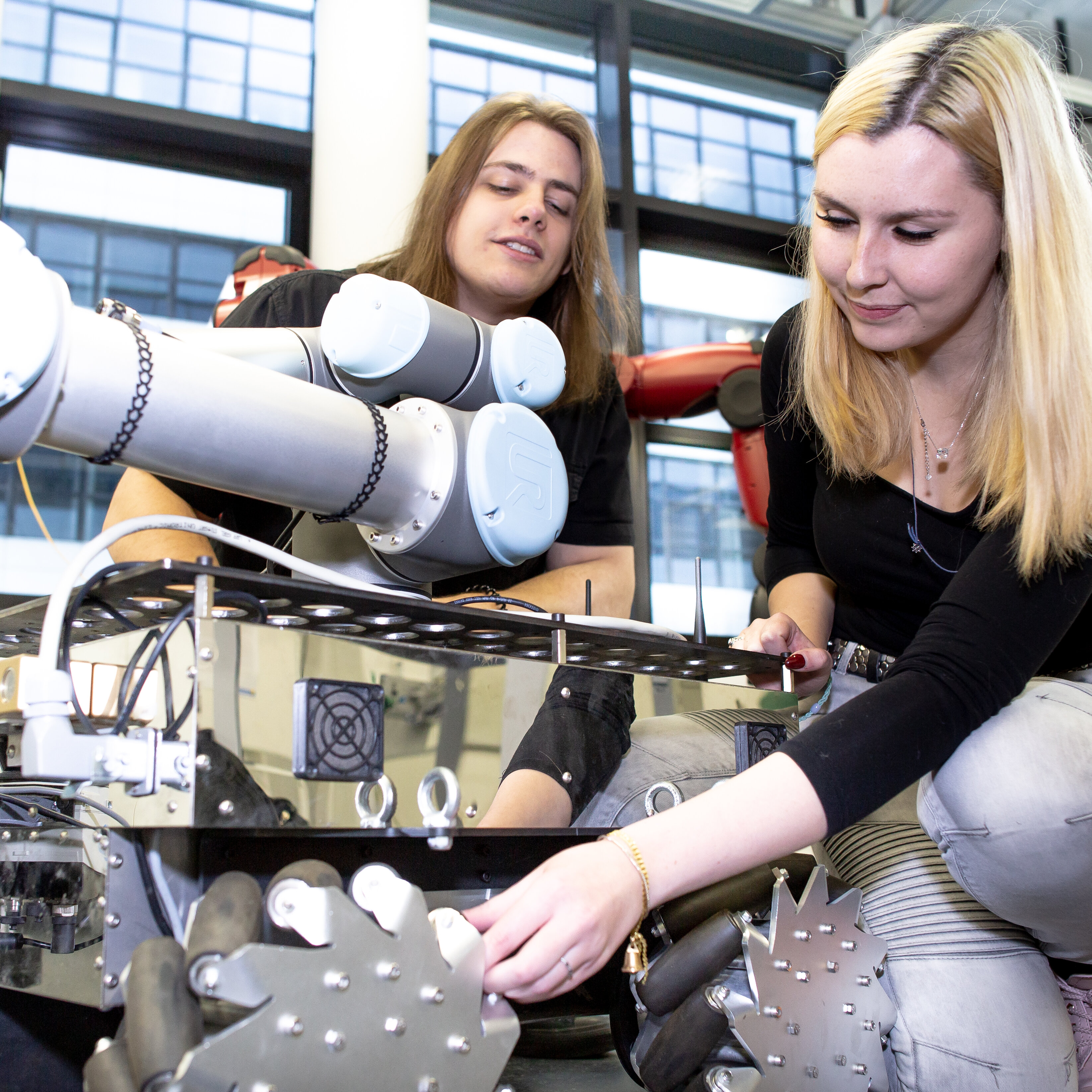 Zwei Studierende arbeiten an einem Roboterarm