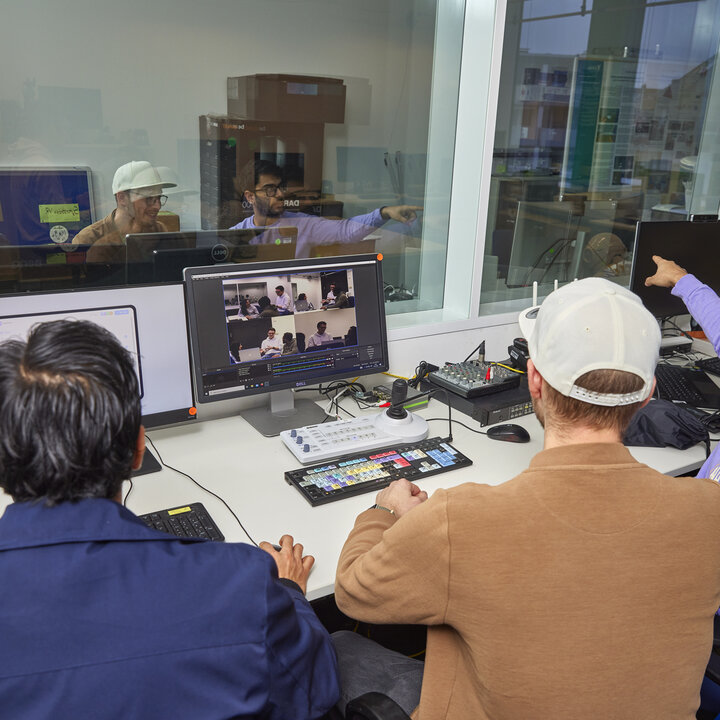 Three students are working together at several monitors in the control room of the usability lab
