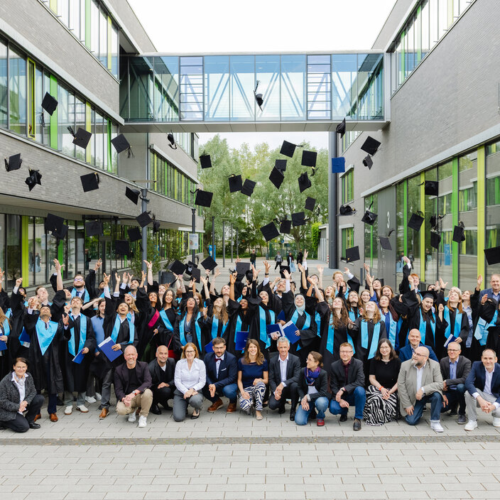 Graduates throw their hats into the air on campus