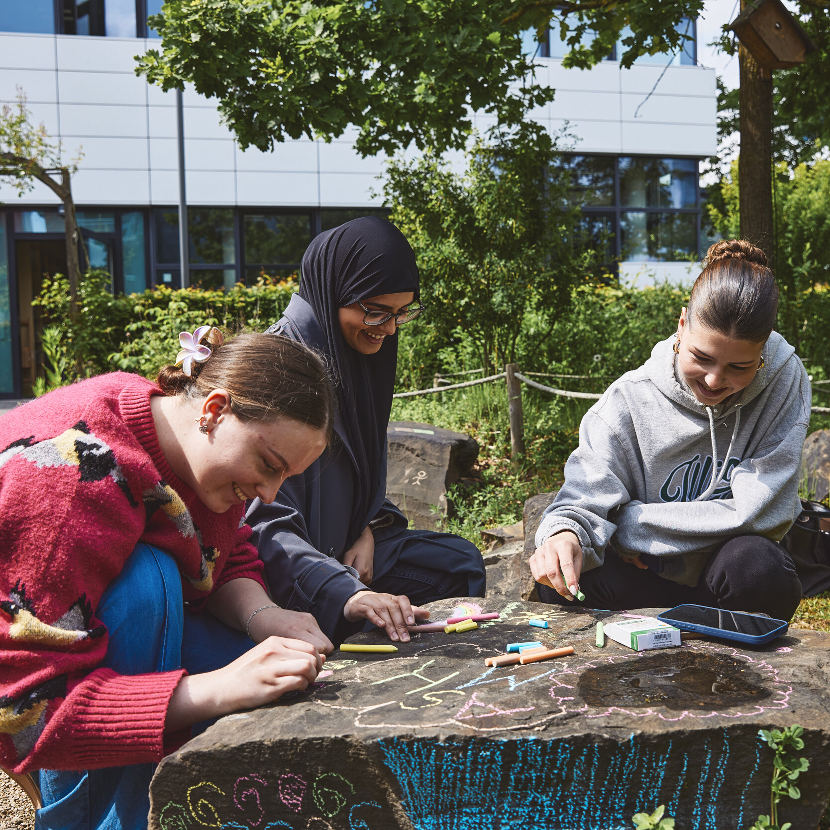 3 Studierende Bemalen einen Findling auf dem Campus Kleve