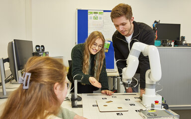 IT mit Kreativität verbinden Studierende arbeiten an einem Projekt mit einem Roboterarm