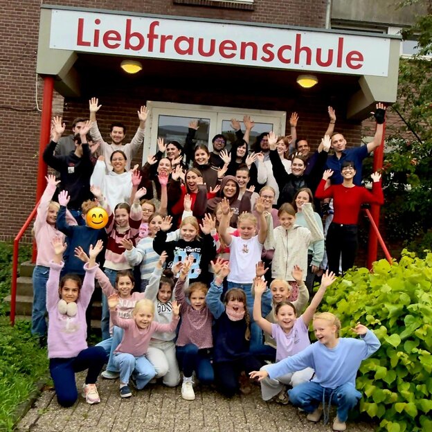 Gruppenfoto von Kindern und Erziehern vor dem Eingang der Liebfrauenschule