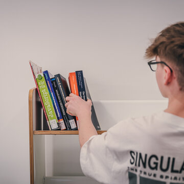 Junge greift nach einem Buch im Bücherregal
