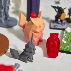 Nahaufnahme von 3D-gedruckten Figuren und kleinen Skulpturen auf einem Tisch.