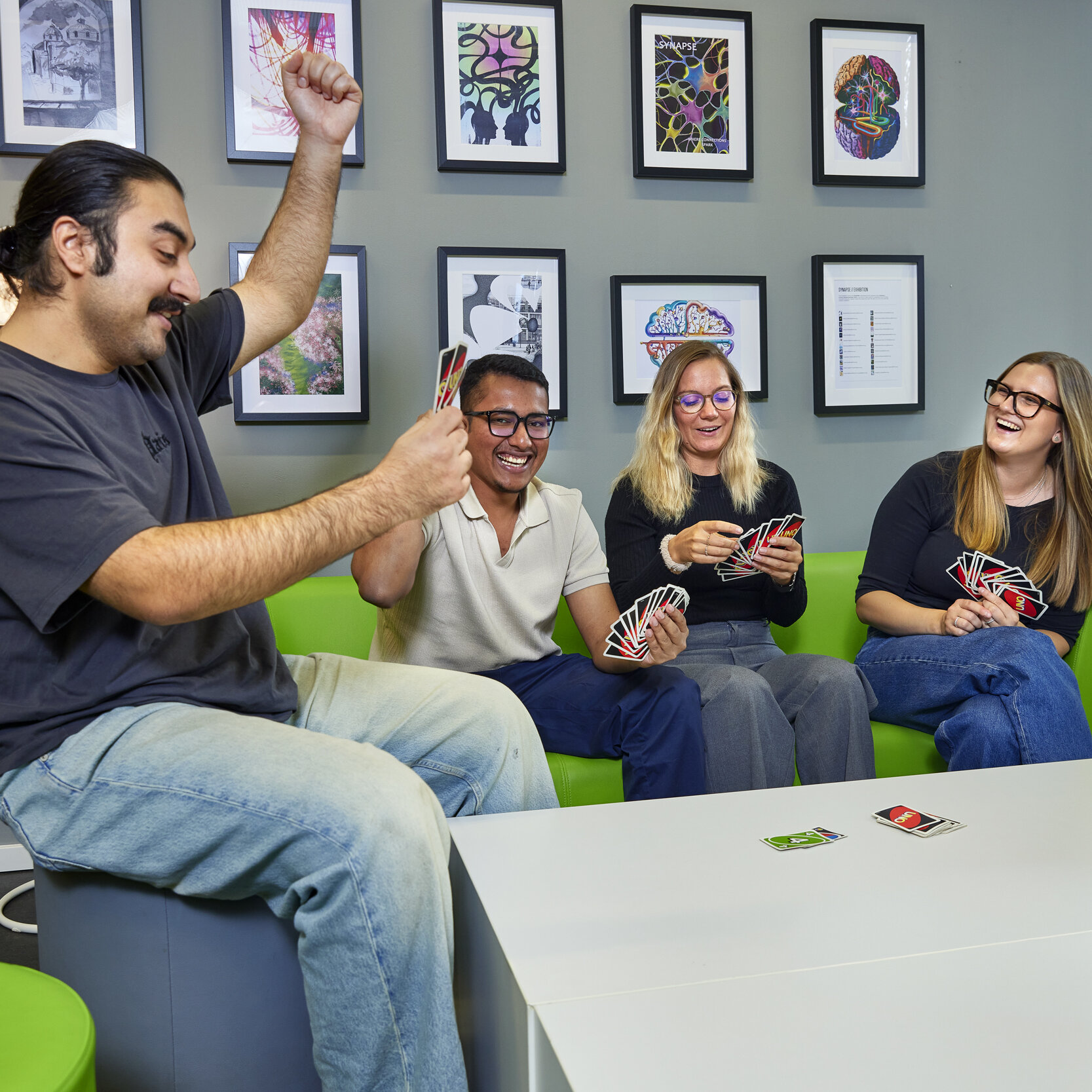 Studierende sitzen zusammen im Synapse-Raum, spielen Uno und lachen.
