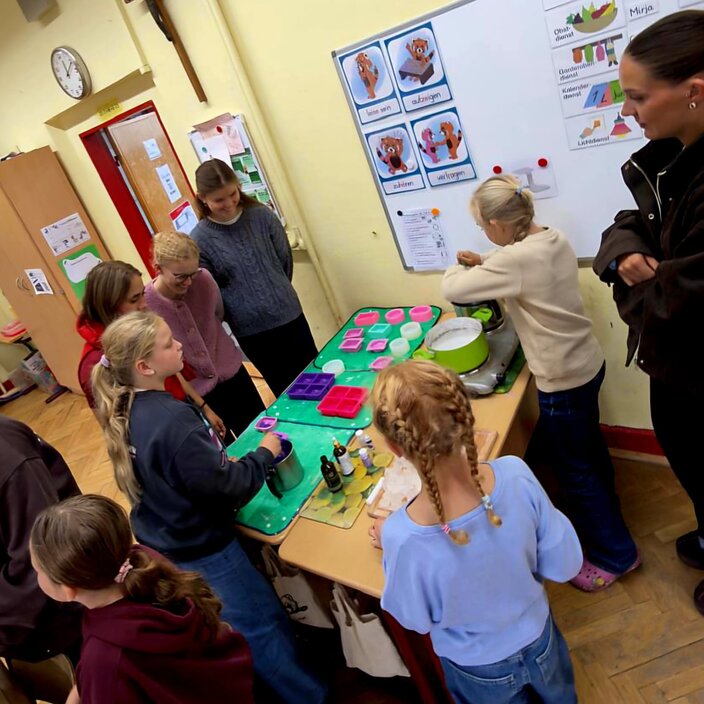 Kinder stehen um einen Tisch in einer Kita und beobachten eine Spielsituation