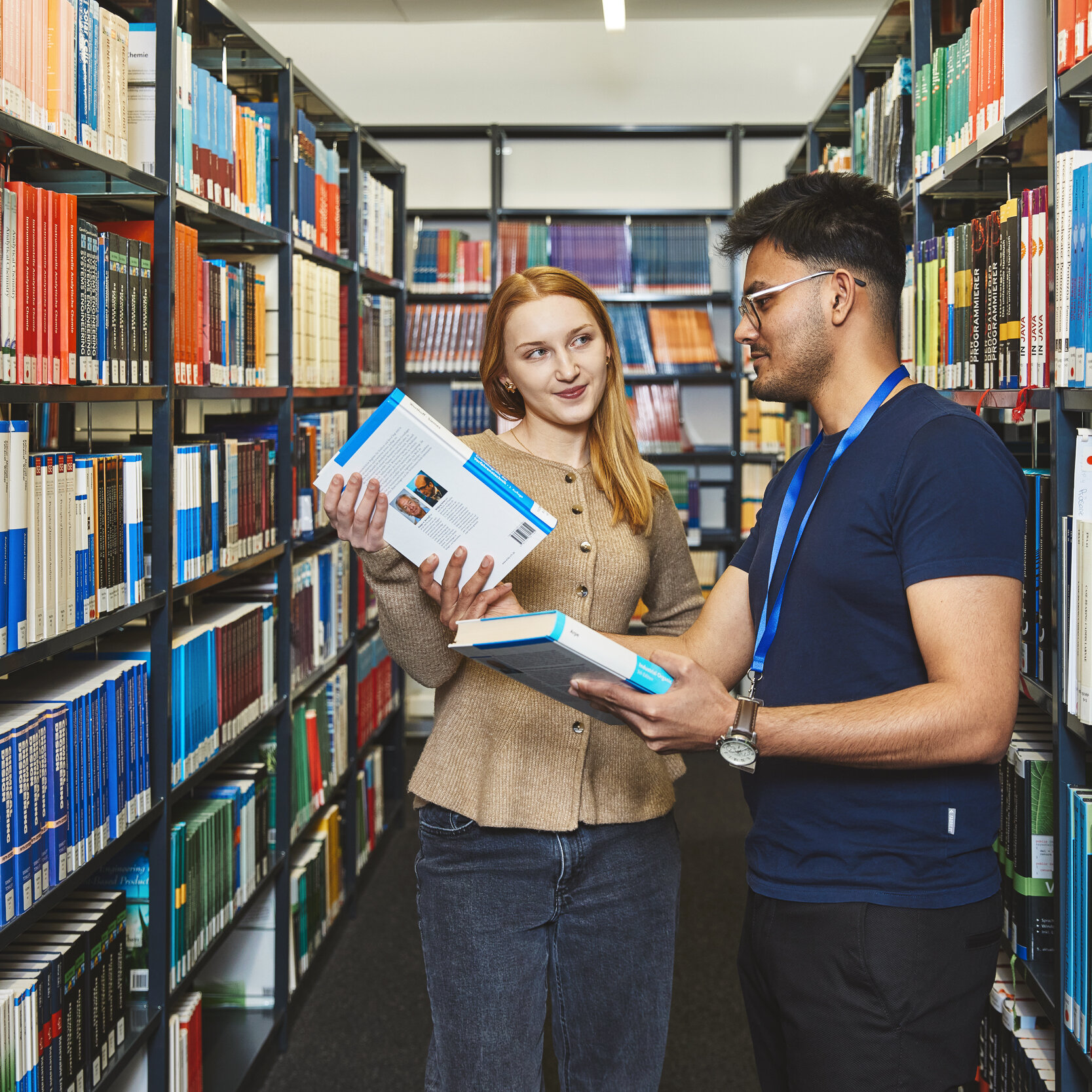 A library member of staff is showing a student some books on the bookshelf at the Kamp-Lintfort Library