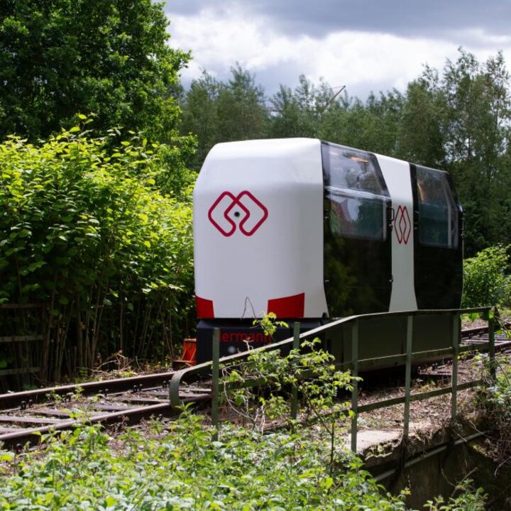 Ein Monocab-Wagon fährt auf einer Bahnschiene durch eine Landschaft