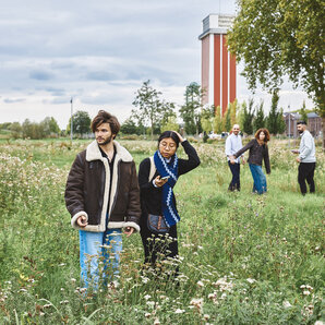 Eine Gruppe von Studierenden geht durch eine Wildblumenwiese.
