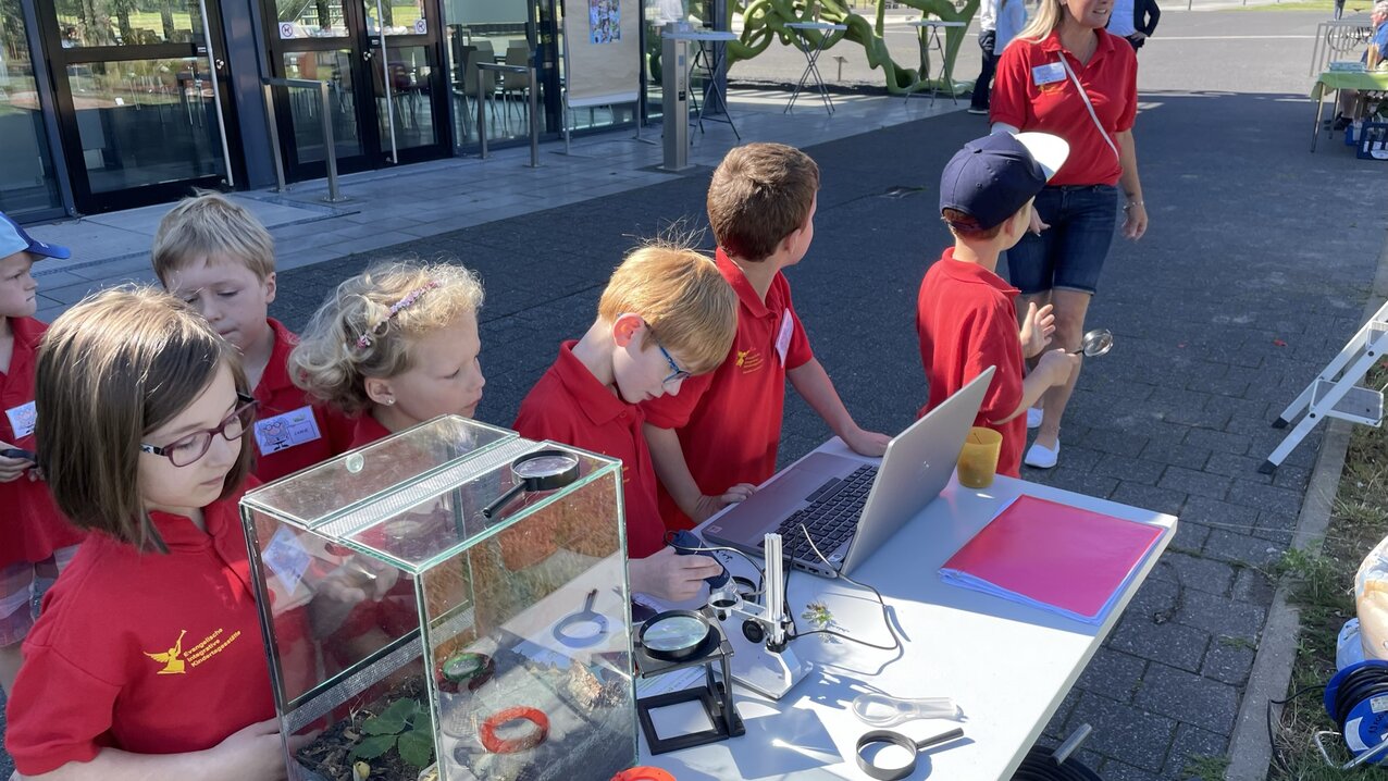 Here, the nursery children are examining soil creatures using a digital magnifying glass and identifying them with the help of the ‘Haus der kleinen Forscher’ soil creature chart.