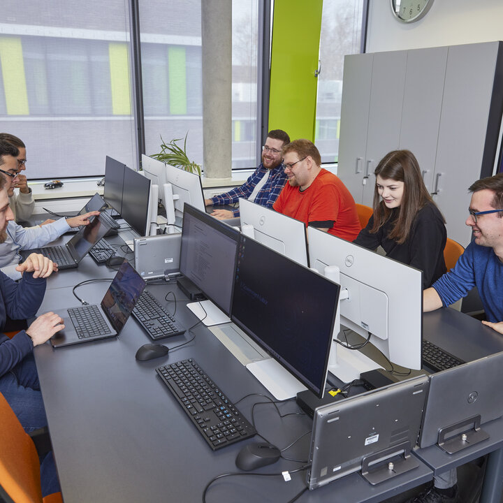 A group of students are sitting at computer workstations, looking at their screens.