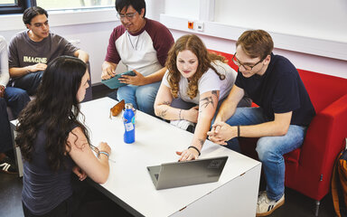 Gelebte Internationalität eine Gruppe Studierender sitzt um auf einem Sofa und arbeiten an einem Laptop zusammen