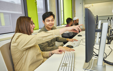 Du machst Daten zu Lösungen Zwei Studierende arbeiten gemeinsam an einem Computer; eine Studentin zeigt auf den Bildschirm.