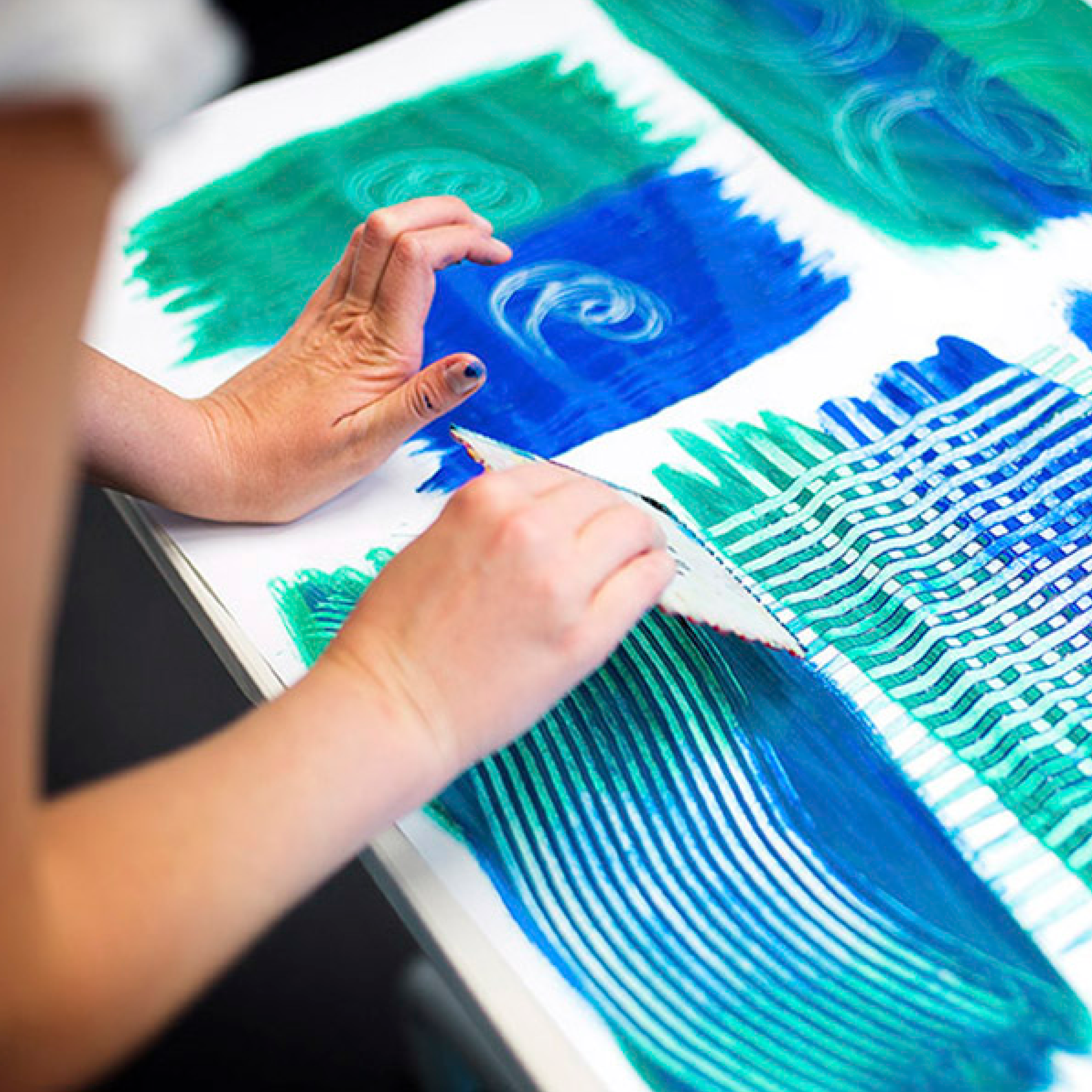 Bildausschnitt mit Händen, die an einem Kunstwerk in Grüntönen arbeiten